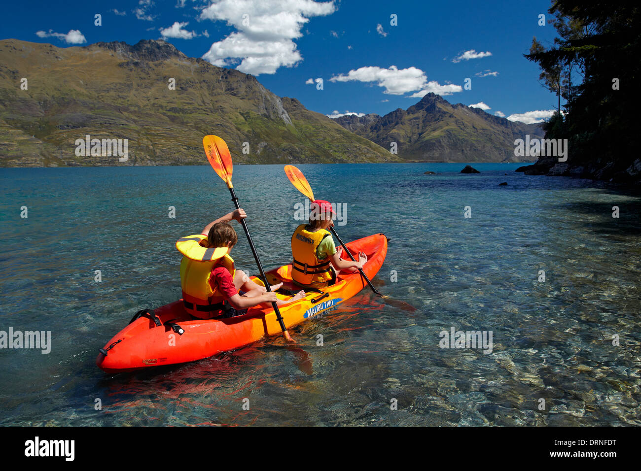 Los niños en kayak, Sunshine Bay, el lago Wakatipu, Queenstown, Otago, Isla del Sur, Nueva Zelanda Foto de stock
