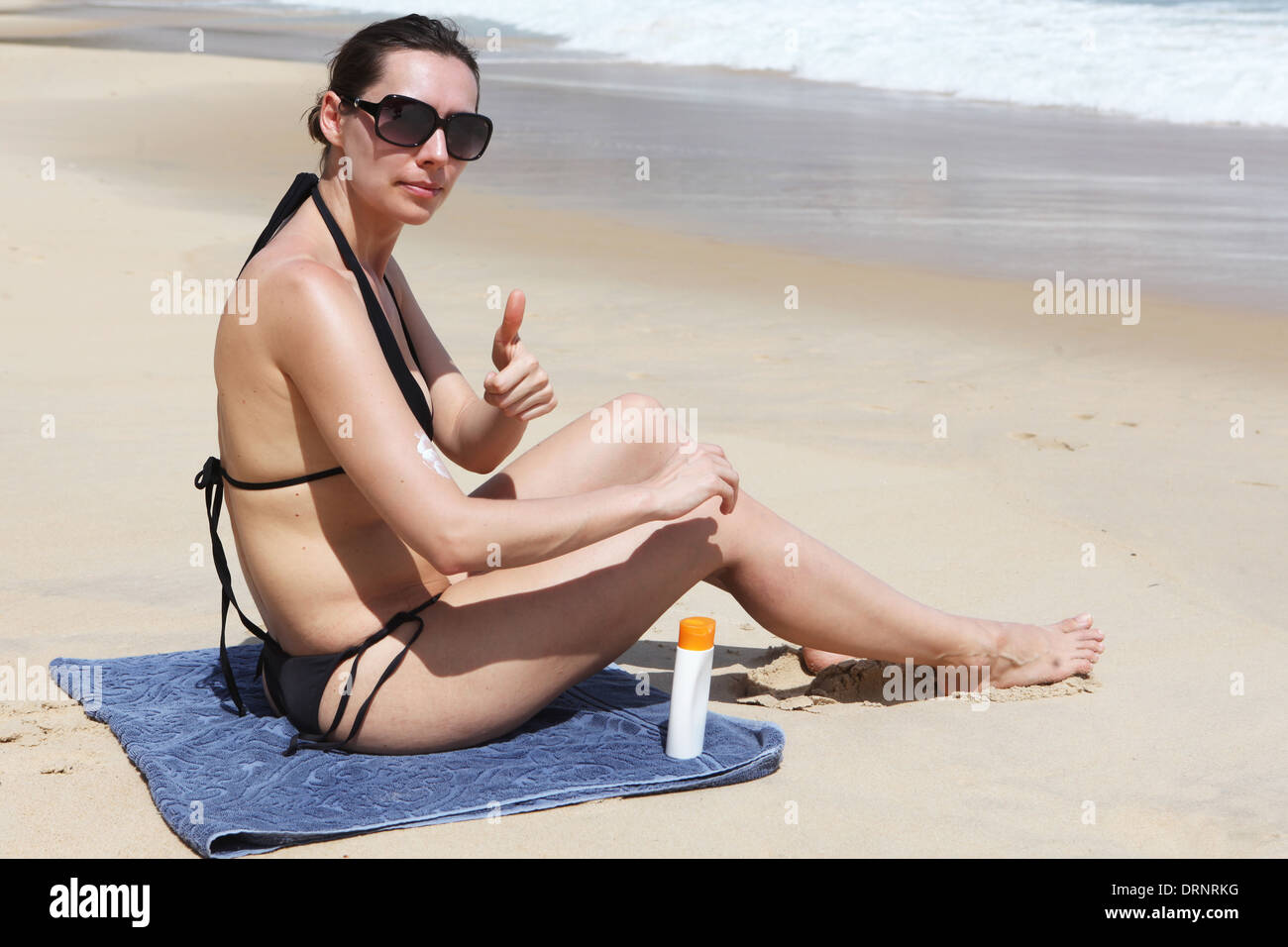 Mujer con protector solar en la playa Foto de stock