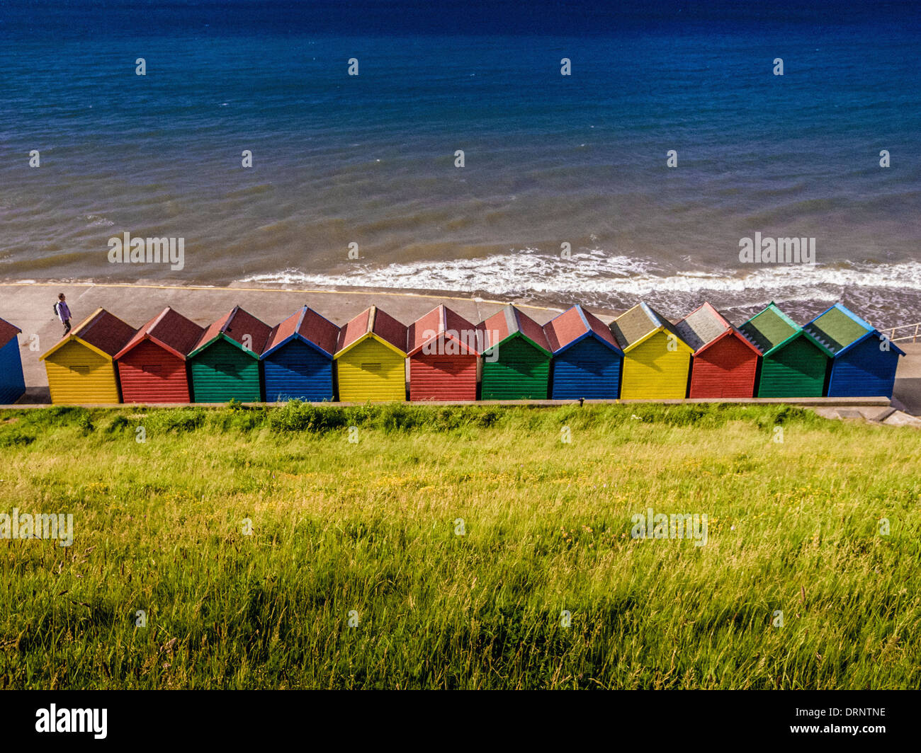Coloridas cabañas de playa en West Cliff, Whitby, North Yorkshire. Fotografiado desde atrás con el mar en el fondo. Foto de stock