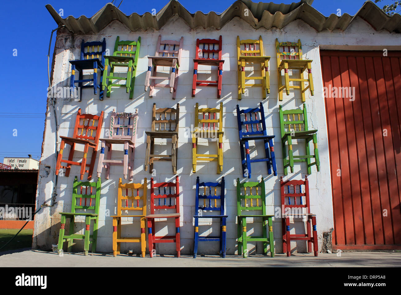 Pared decorada con sillas de madera de colores, Tepotzotlan, México Foto de stock