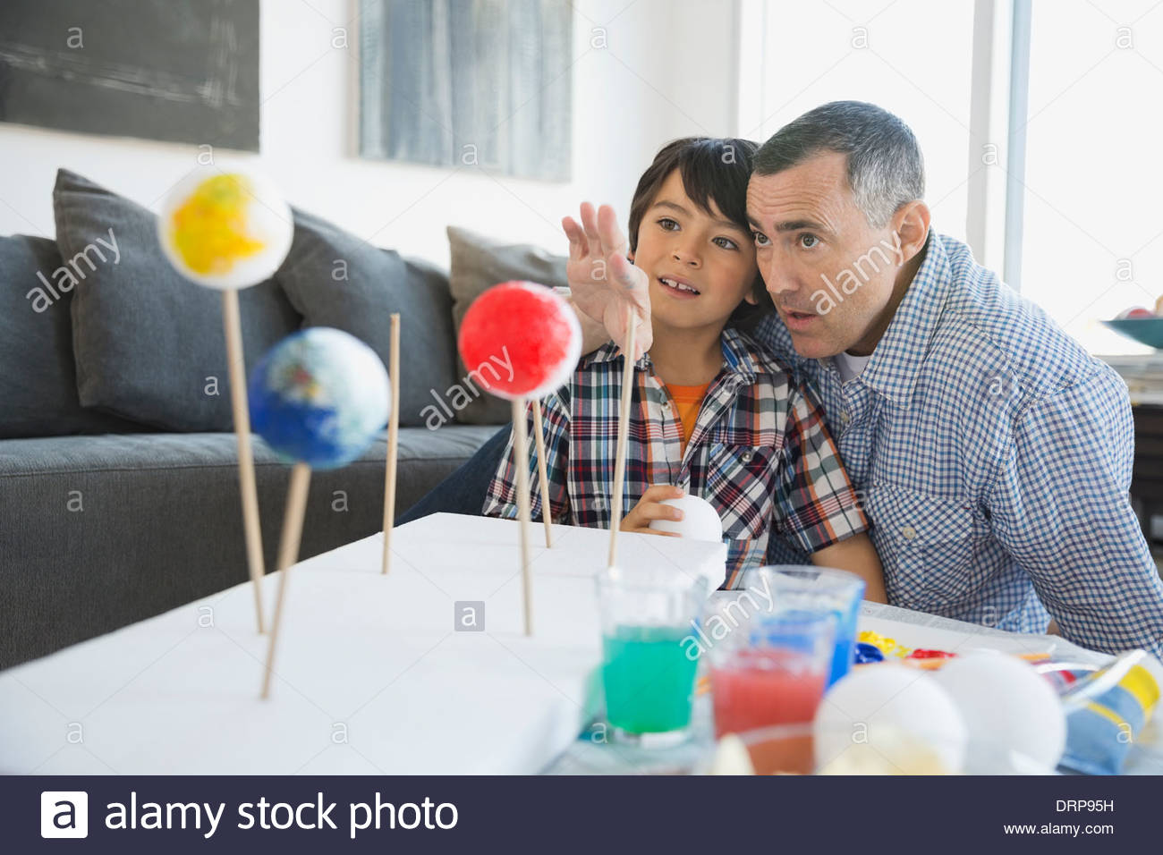 Padre explicando el modelo del sistema solar al hijo en casa Foto de stock