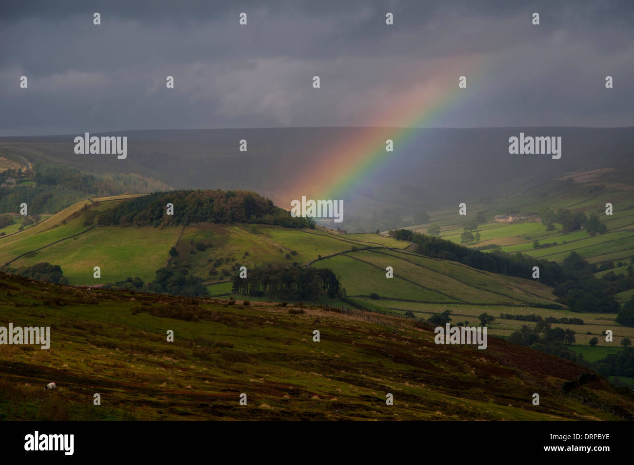 Las nubes de lluvia y un arco iris sobre Rosedale, visto desde la chimenea en el borde del Banco Spaunton Moor en el North York Moros NP Foto de stock