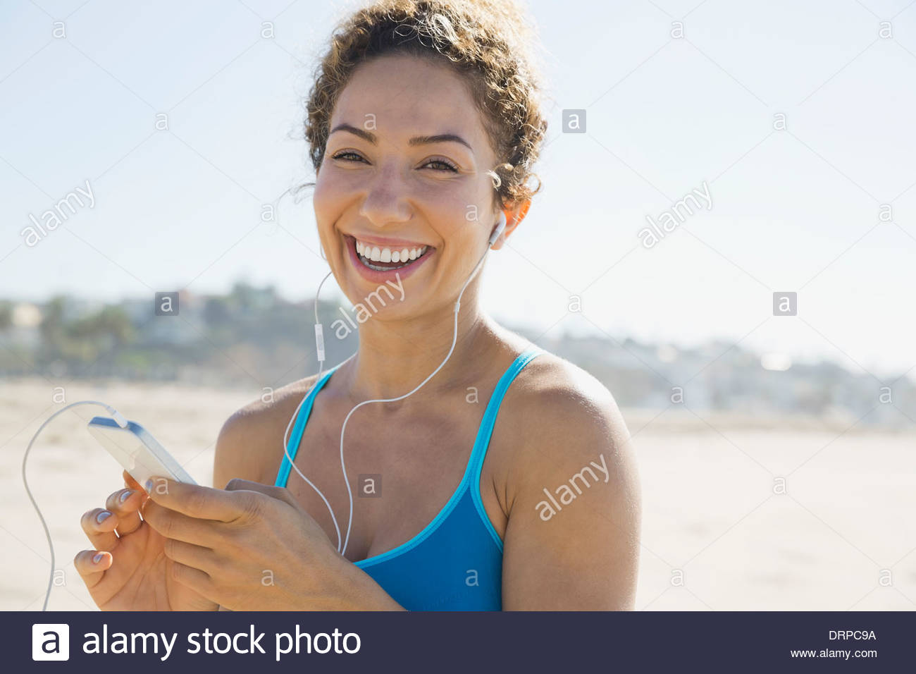 Retrato de mujer activa escuchando música en la playa Foto de stock
