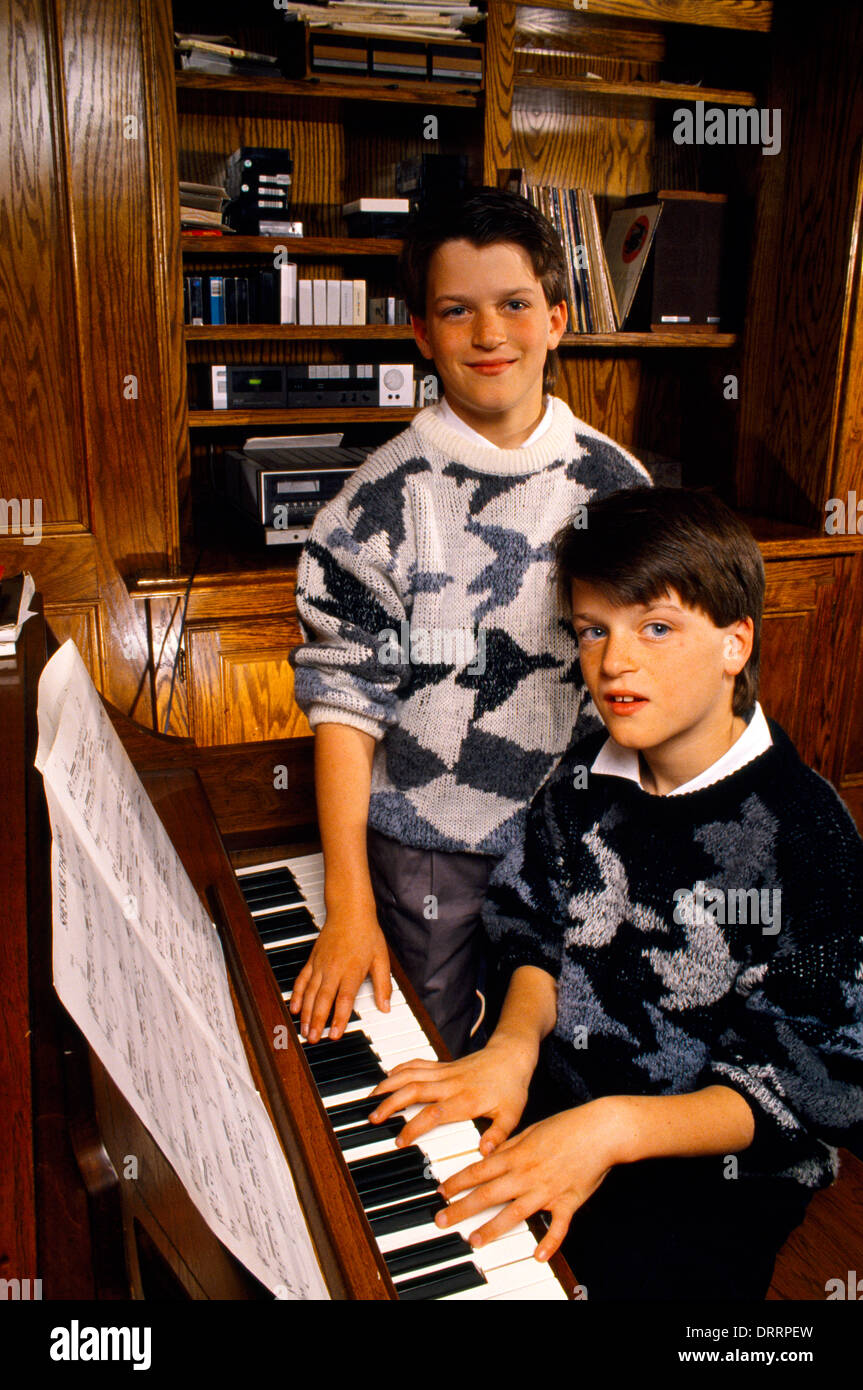 Gemelos idénticos sentado al piano EE.UU. Foto de stock