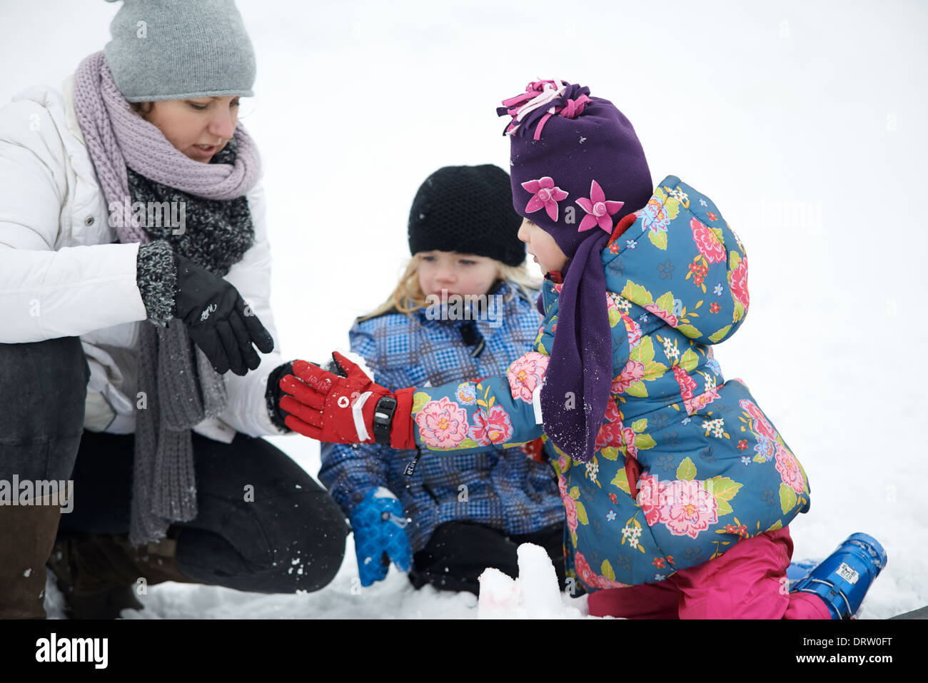 Madre con hijas jugando con la nieve, el invierno Foto de stock