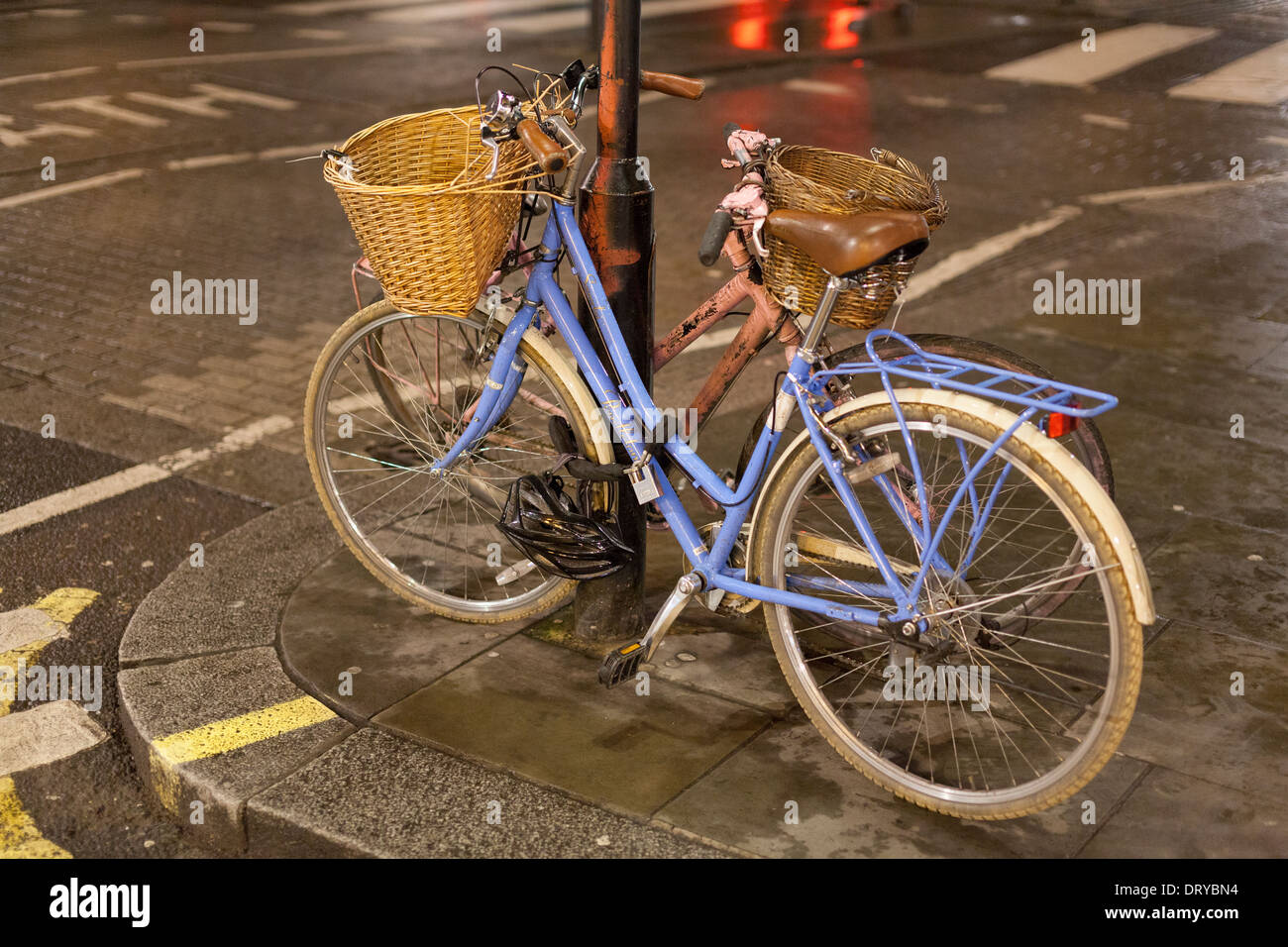 Bicicletas encadenadas a poste de la luz por la noche,West End, Londres, Inglaterra Foto de stock