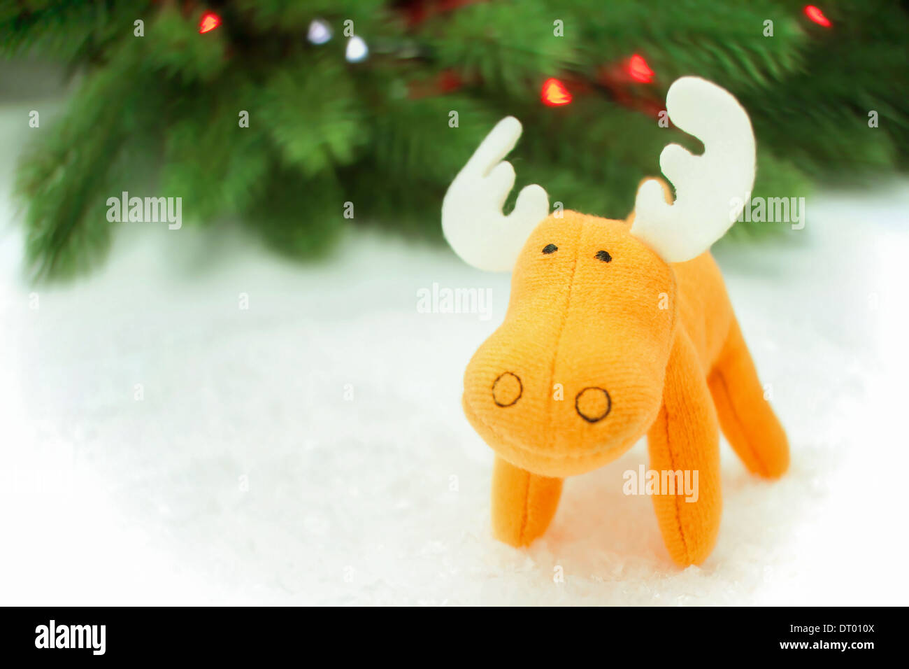 Escena de juguete con orange alces en nieve artificial con pino en fondo Foto de stock