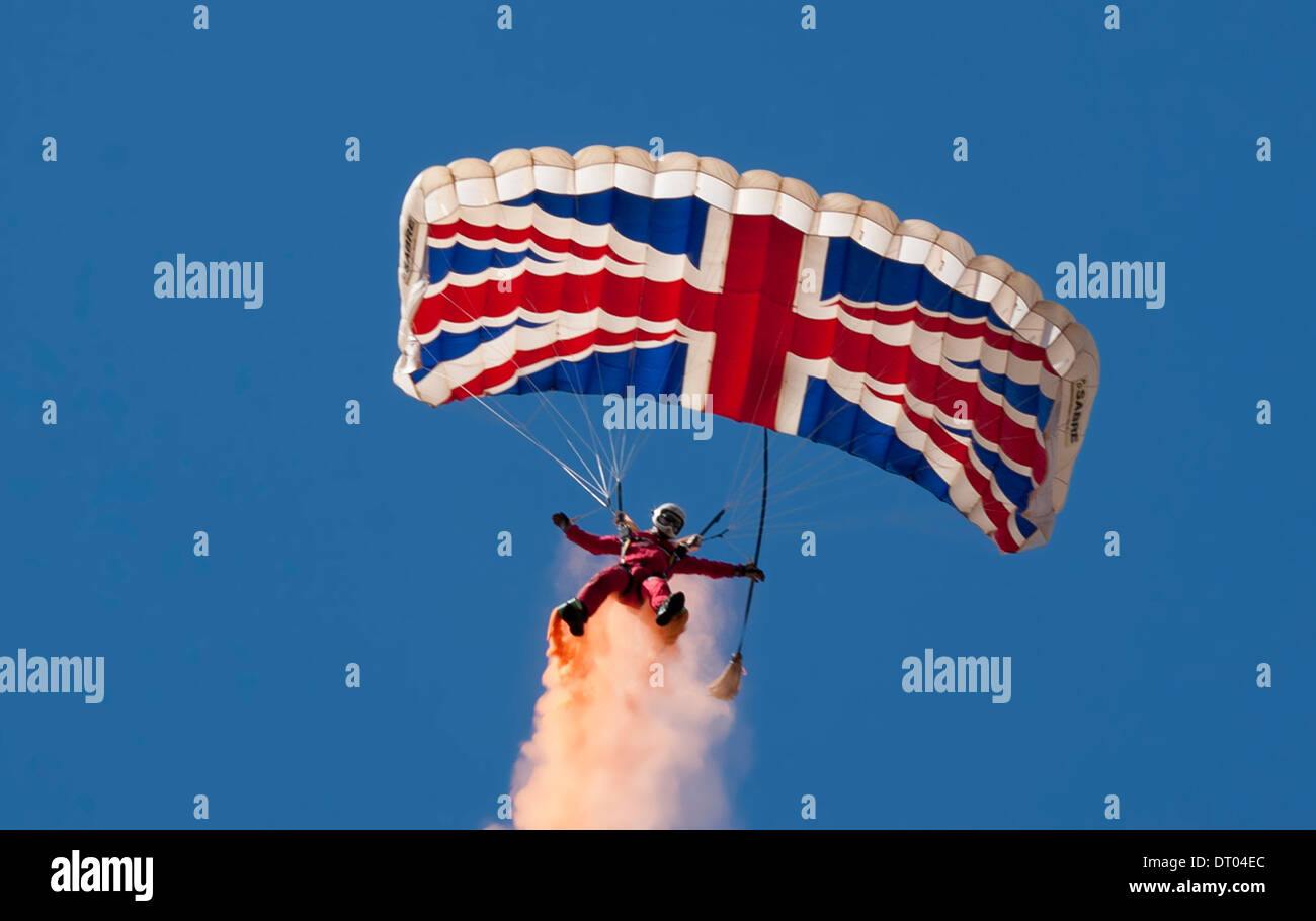 Un paracaídas de los diablos rojos mostrar equipo aterrizaba en los colores de la bandera británica tomadas contra un cielo azul claro Foto de stock
