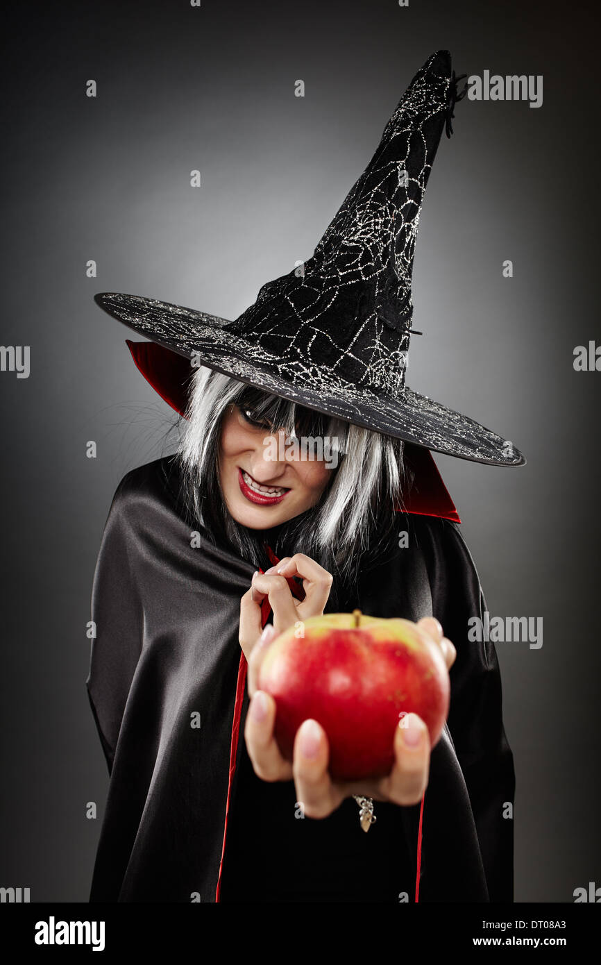 Primer plano de una bruja terrorífica ofreciendo una manzana envenenada Foto de stock