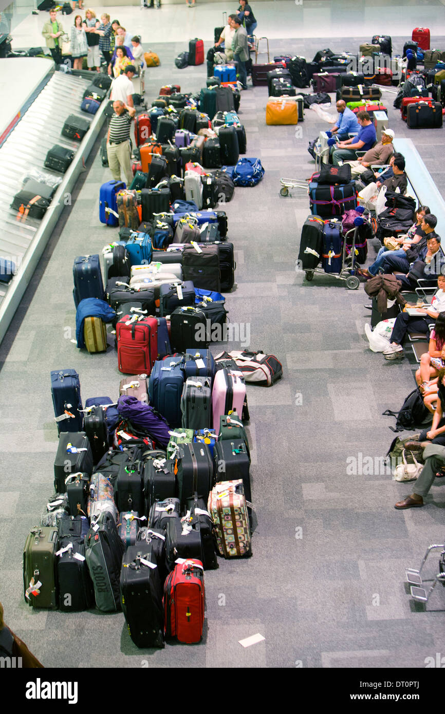 Los viajeros esperan en un aeropuerto en el carrusel de equipaje. Foto de stock