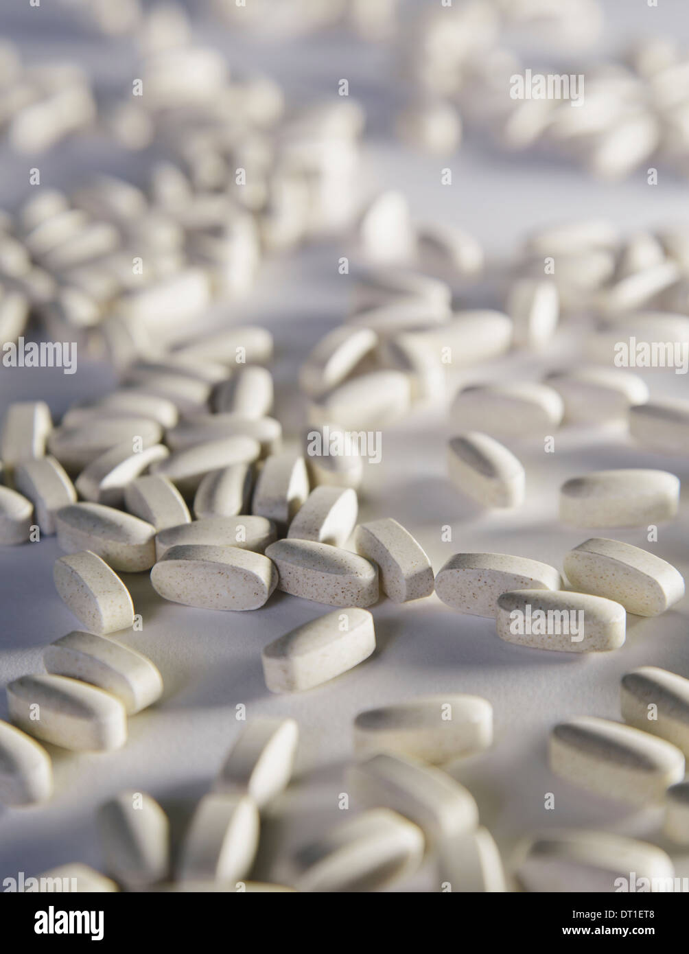 Suplementos de vitamina C blanca ovalada comprimidos tomados por razones de salud repartidas sobre un fondo blanco. Foto de stock