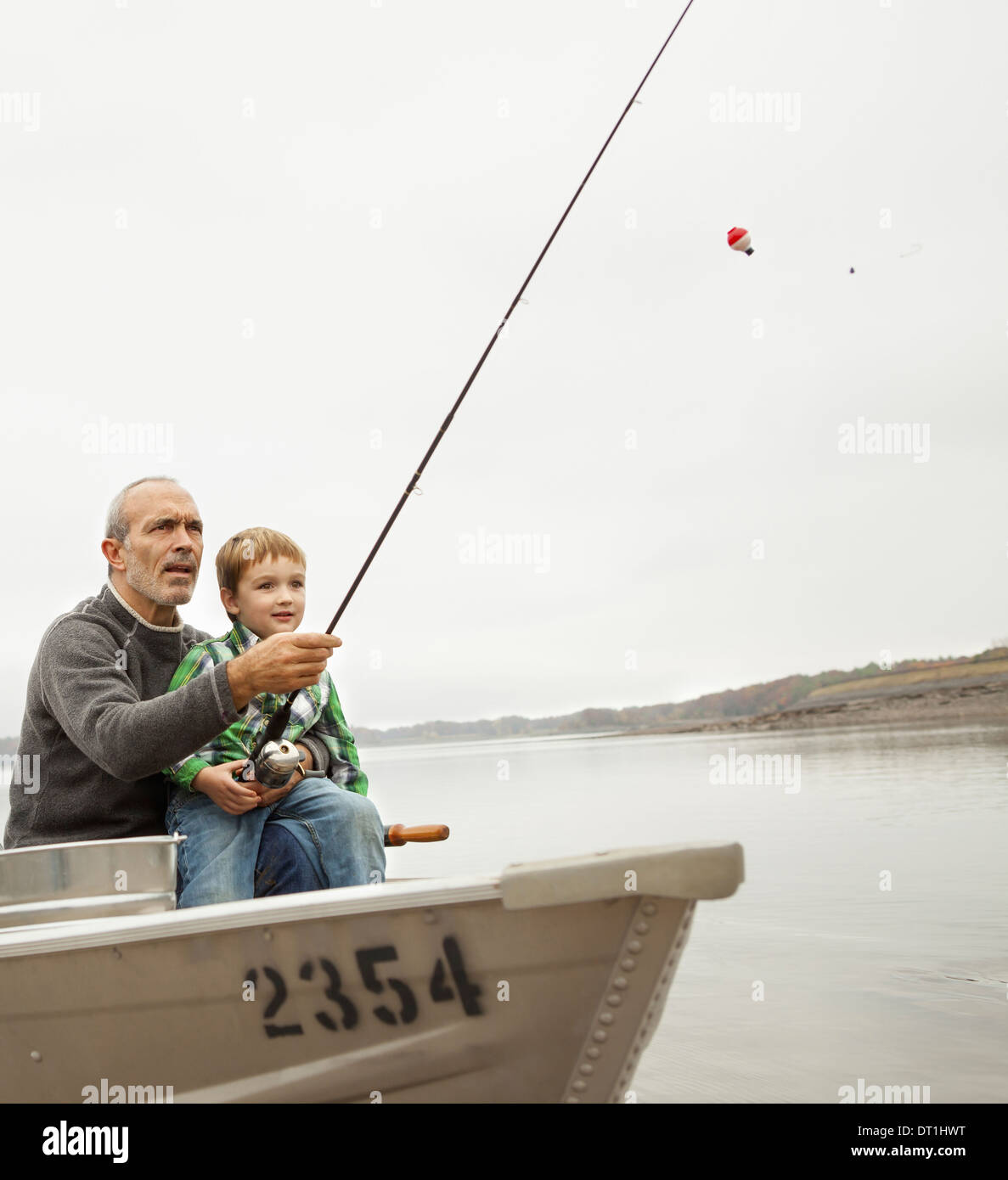 Un día en el lago de Ashokan un hombre mostrando un muchacho cómo pescar sentado en un barco Foto de stock