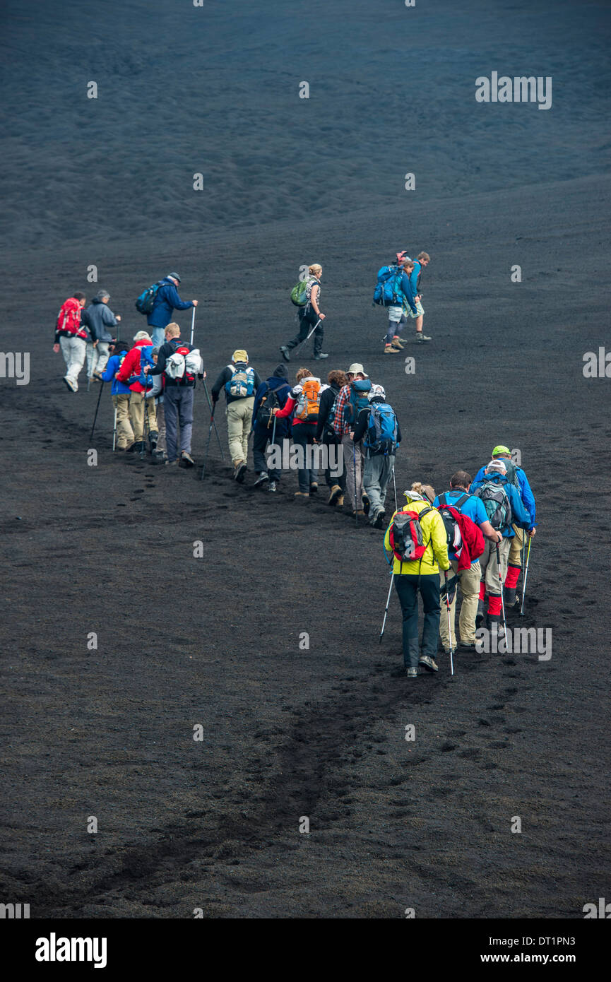 Los turistas que caminan en una línea a través de la arena de lava del volcán Tolbachik, Kamchatka, Rusia, Eurasia Foto de stock