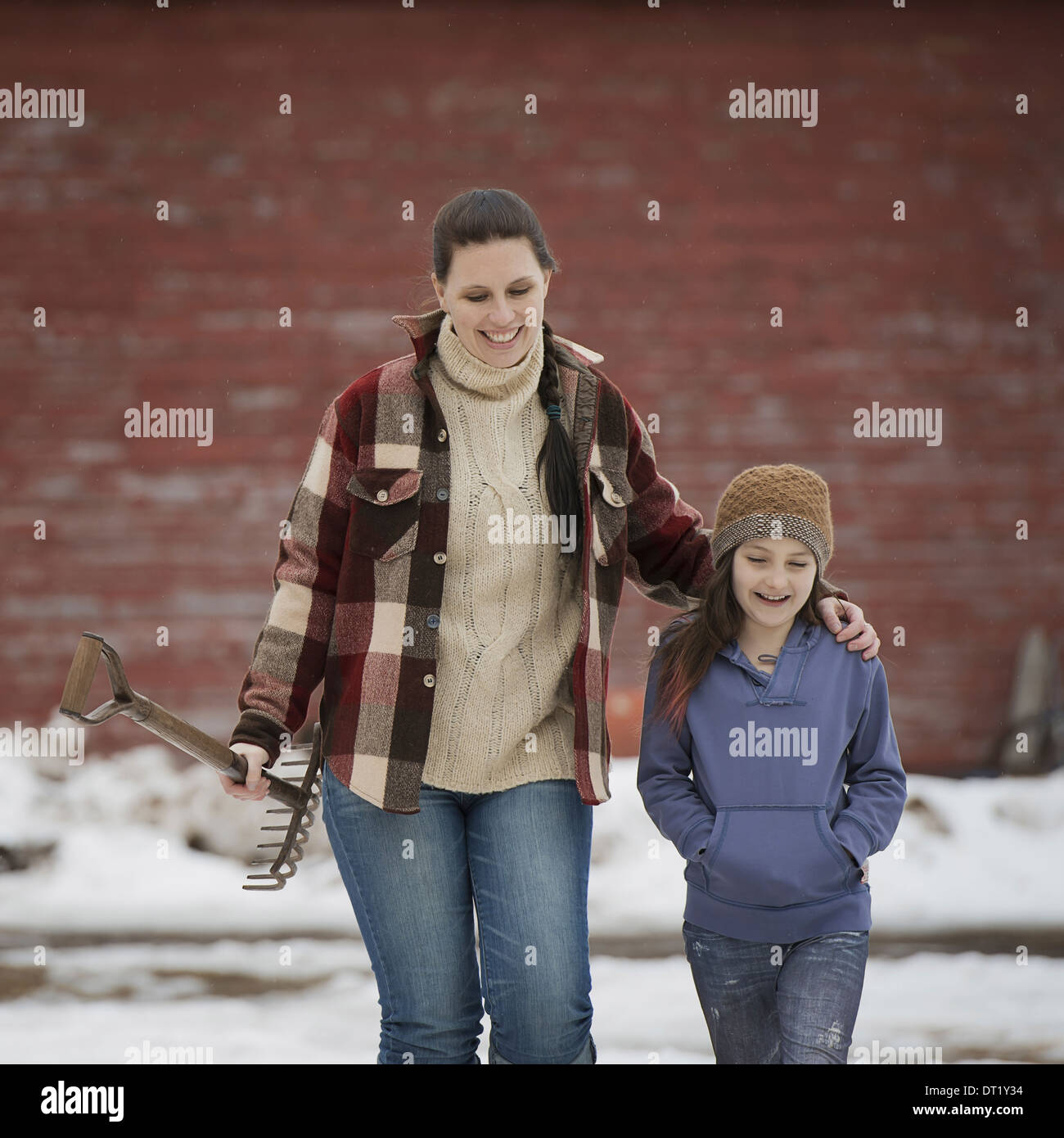 Una mujer y una niña caminando a través de un corral cubiertos de nieve. Foto de stock