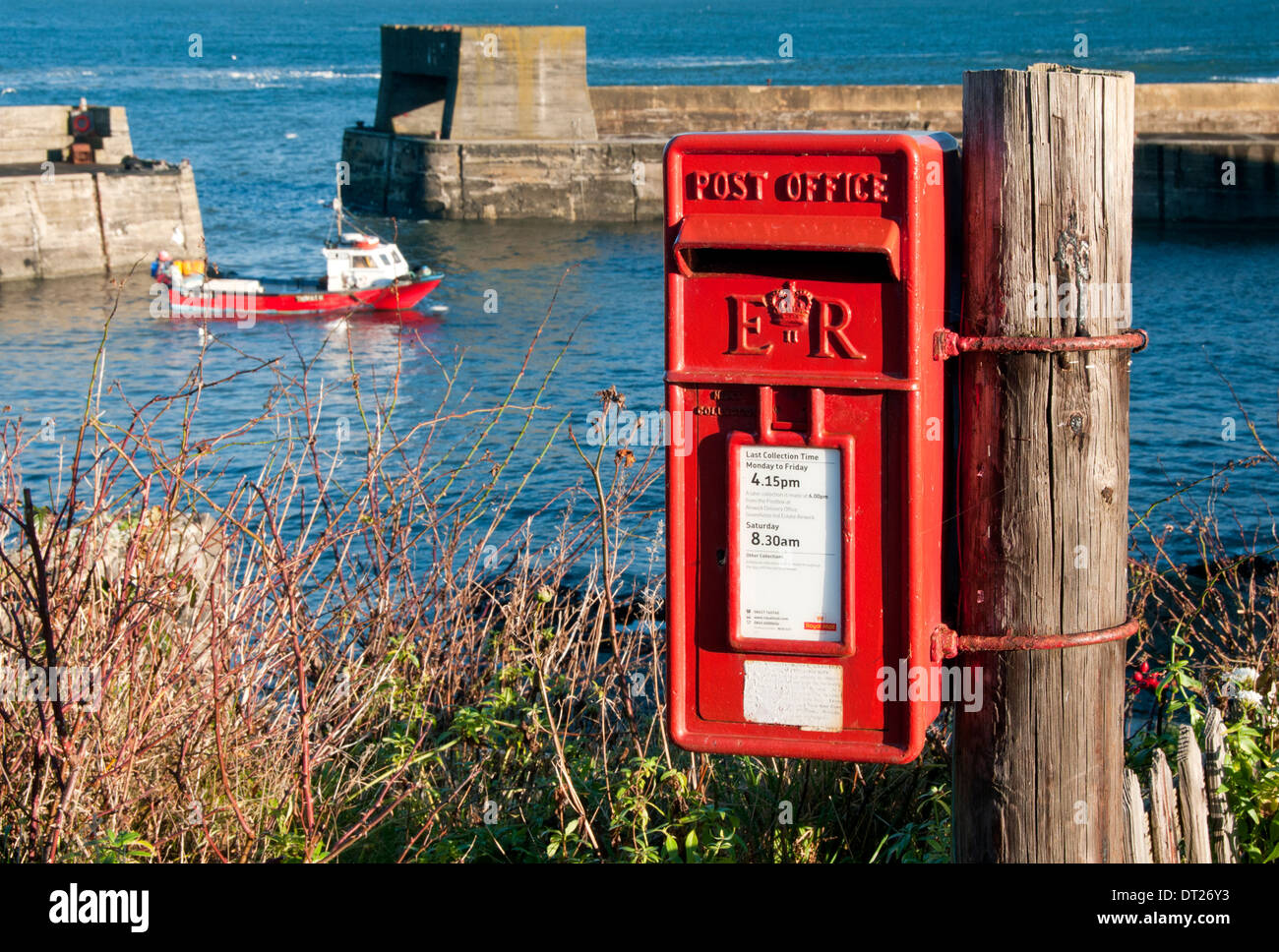 Casilla postal británico de color rojo brillante en el puerto en la aldea de Craster, Craster, Northumberland, Inglaterra, Reino Unido. Foto de stock