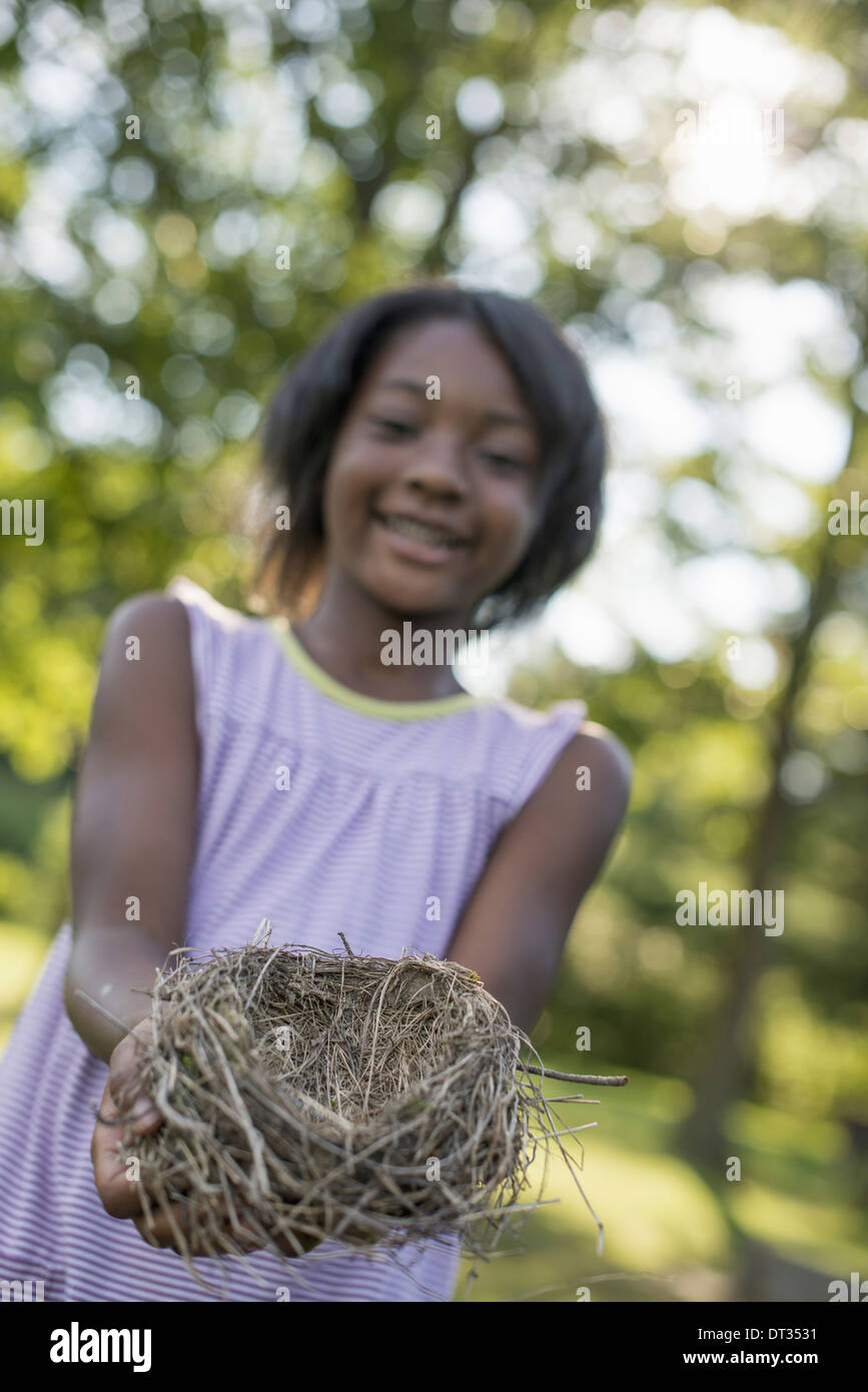 Un niño una niña sonriente y manteniendo un nido de pájaro en sus manos Foto de stock