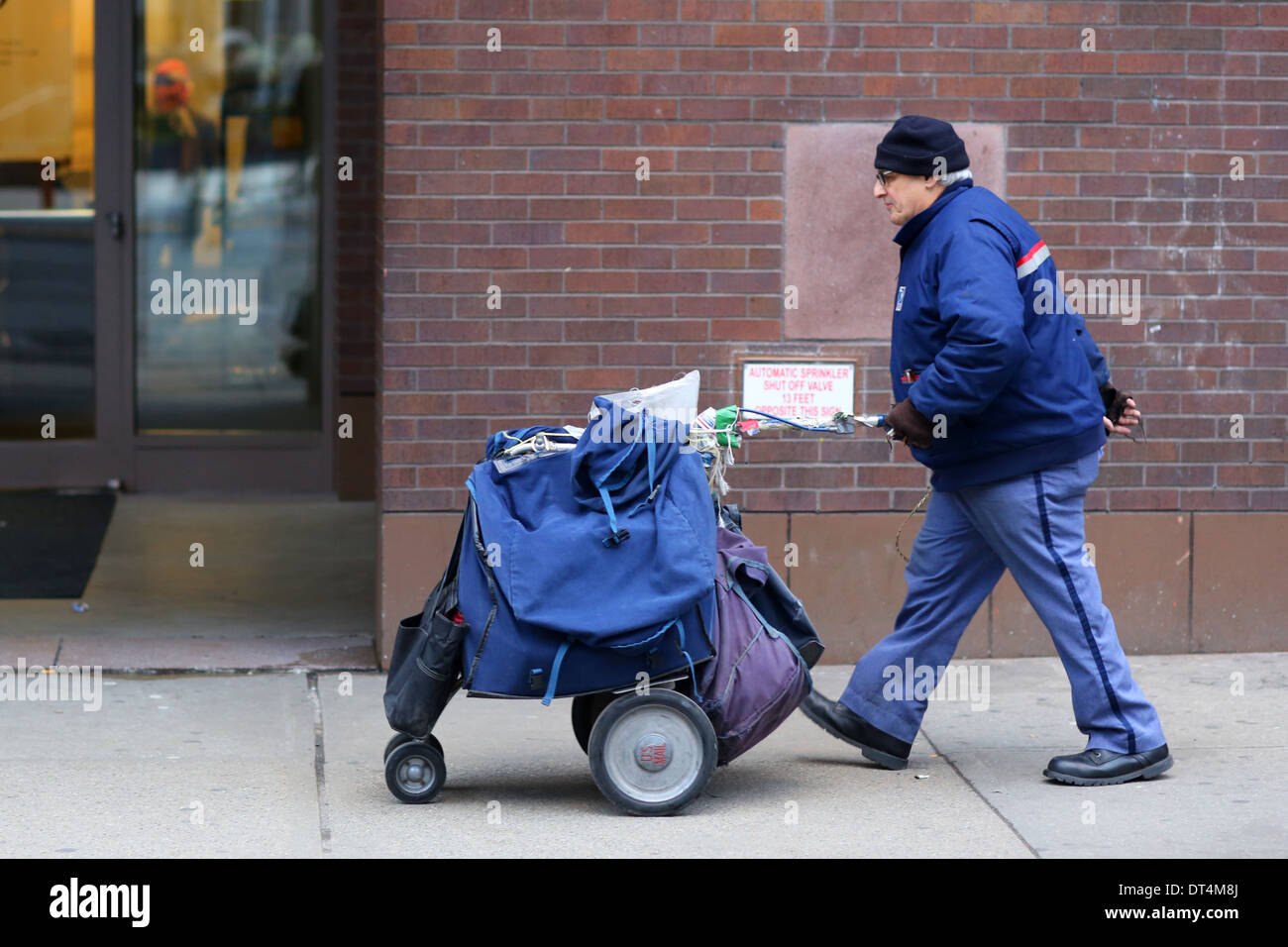 Una portadora de cartas USPS con un carro de correo satchel en la ciudad de Nueva York Foto de stock