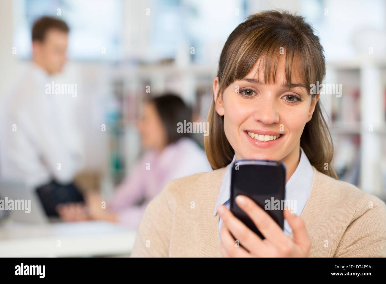 Alegre empresaria utilizando un teléfono inteligente en la oficina Foto de stock