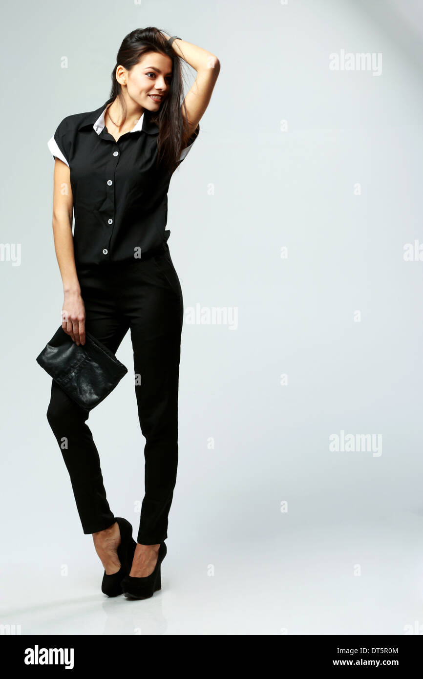 Feliz joven mujer ropa formal en negro sobre fondo gris permanente  Fotografía de stock - Alamy