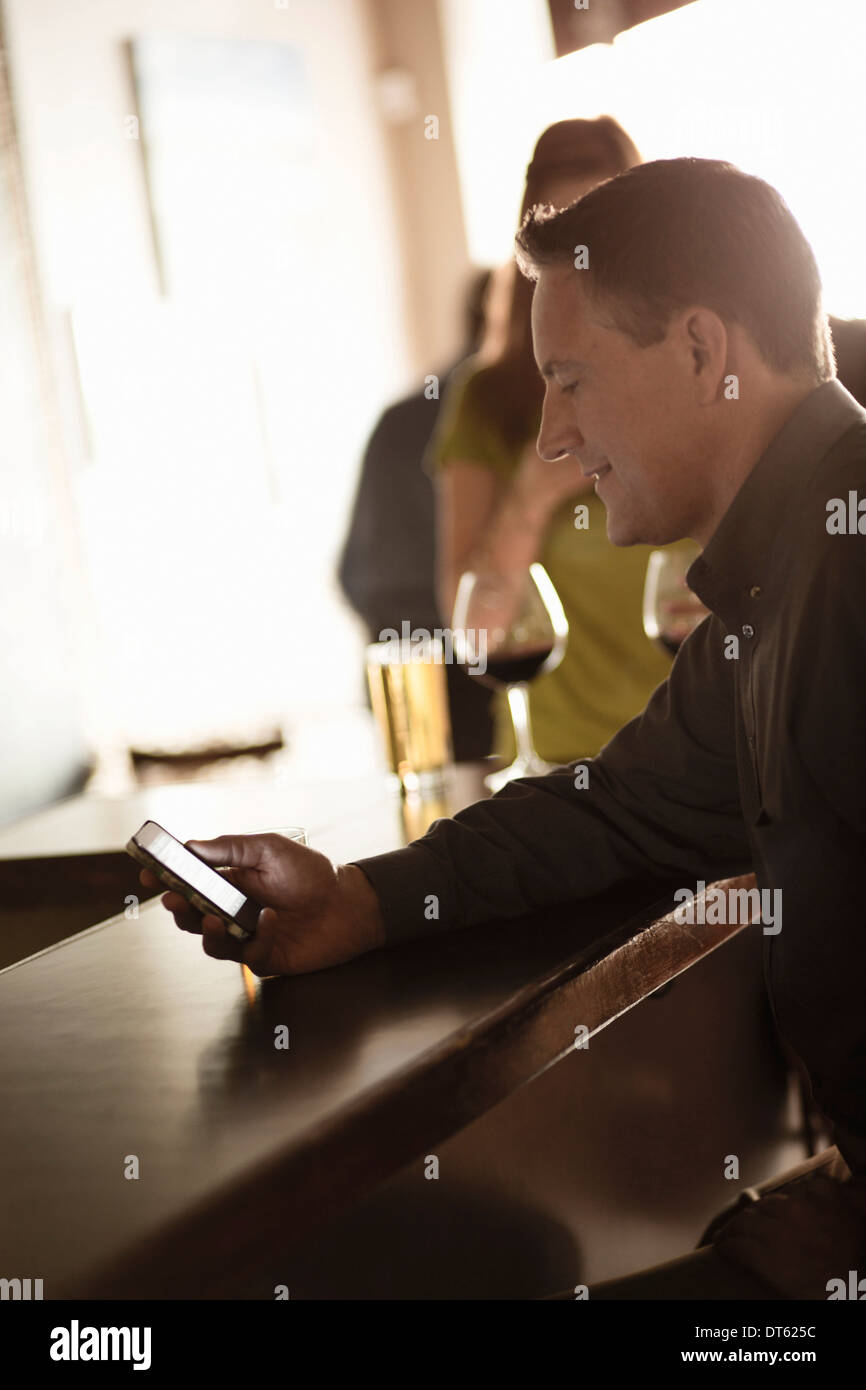 El empresario busca en el celular en un bar de vinos Foto de stock