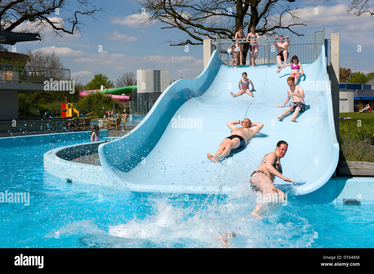 La gente se desliza sobre un tobogán de agua de una piscina pública Foto de stock