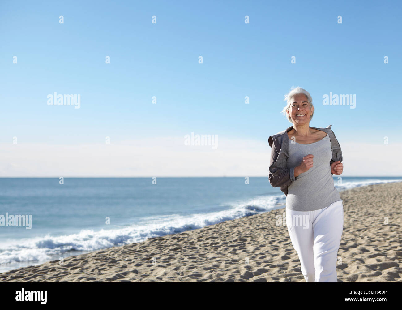 Mujer madura, trotar en la playa Foto de stock