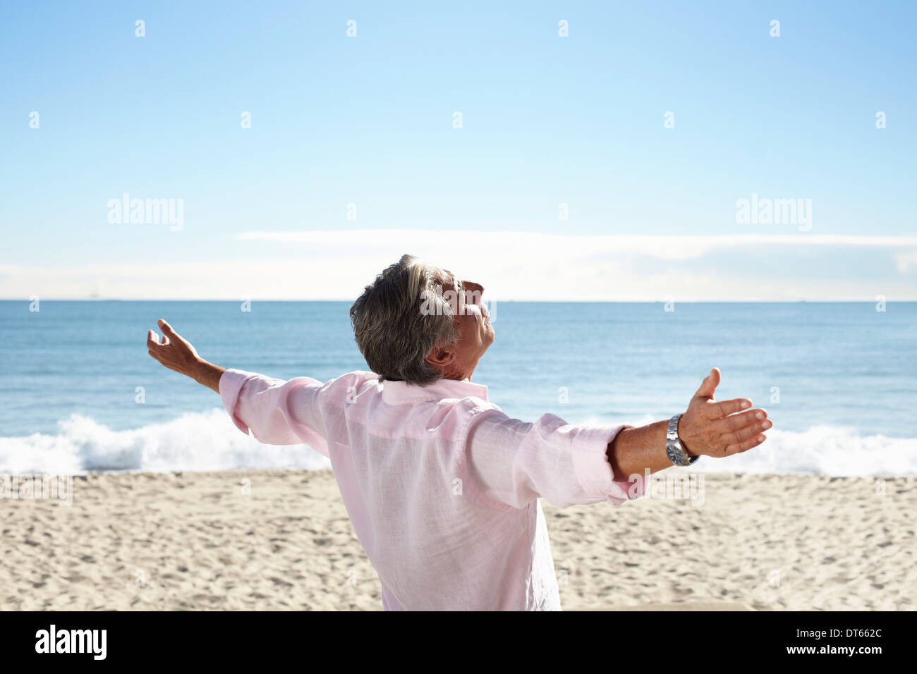 Hombre senior en la playa con brazos extendidos Foto de stock