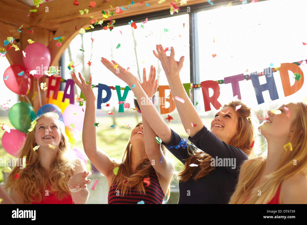 Cuatro adolescentes celebrando con confeti en la fiesta de cumpleaños Foto de stock