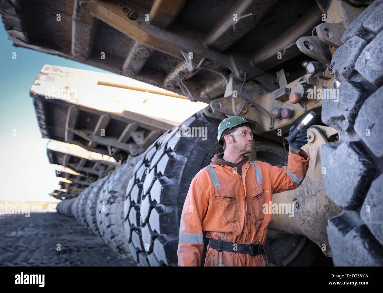 La minera de carbón inspecciona dumper truck de la banda de rodadura del neumático en la mina de carbón superficial Foto de stock