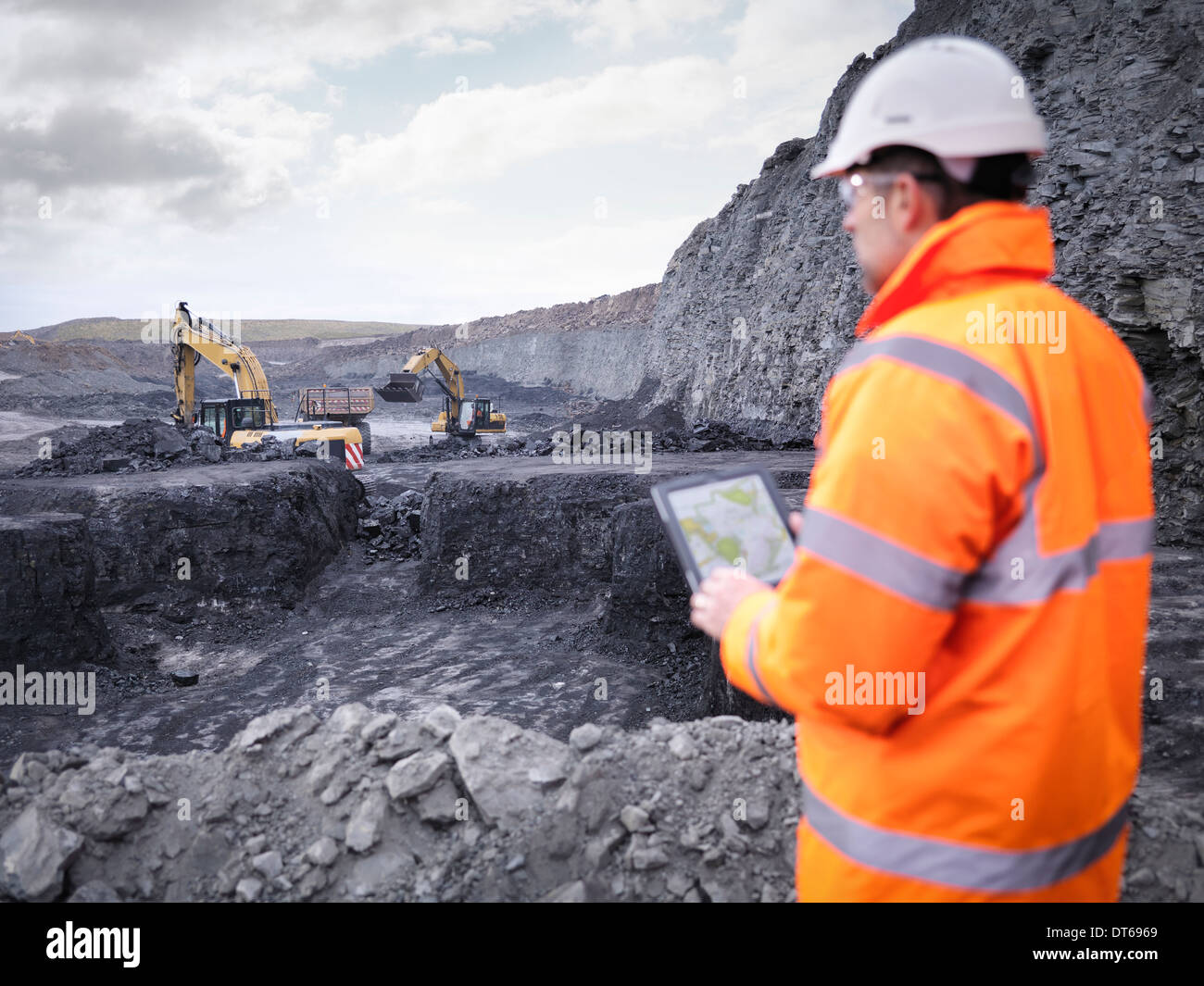 Miner comprueba planes sobre la tableta digital en la mina de carbón superficial Foto de stock