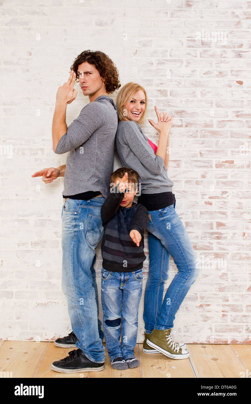 Retrato de estudio de pareja e hijo haciendo gestos con la mano la pistola Foto de stock