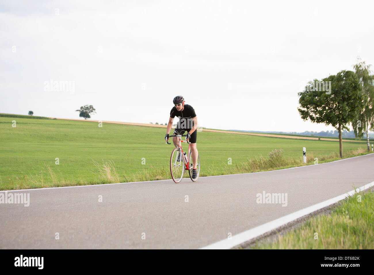 Hombre maduro en bicicleta a lo largo de country road Foto de stock