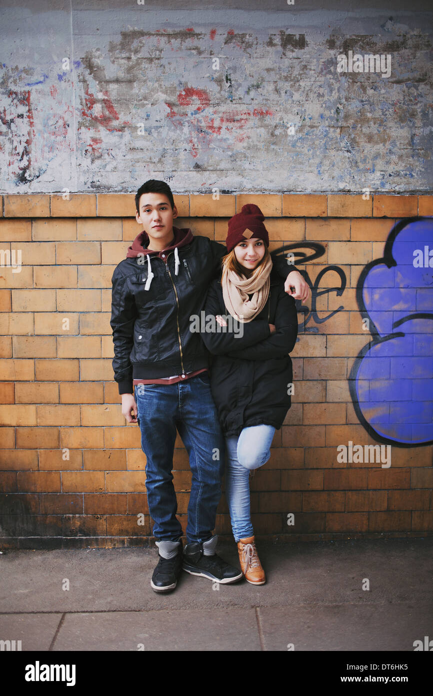 Longitud total retrato de joven apuesto hombre de pie con su hermosa novia apoyado contra una pared. Foto de stock