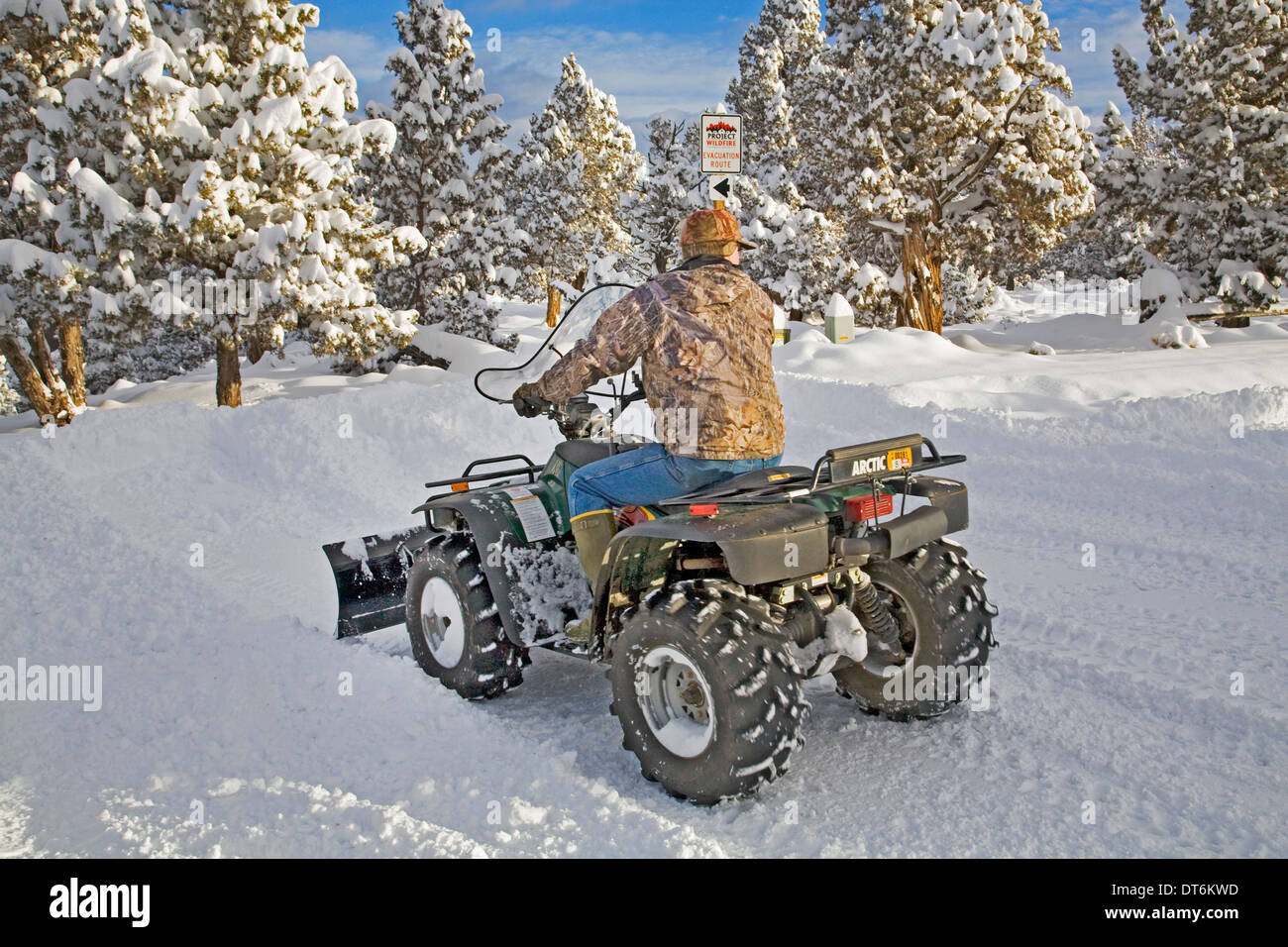 Una persona de la tercera edad los arados de nieve con un ATV, vehículo todo terreno, después de una gran tormenta de nieve en el centro de Oregon. Foto de stock
