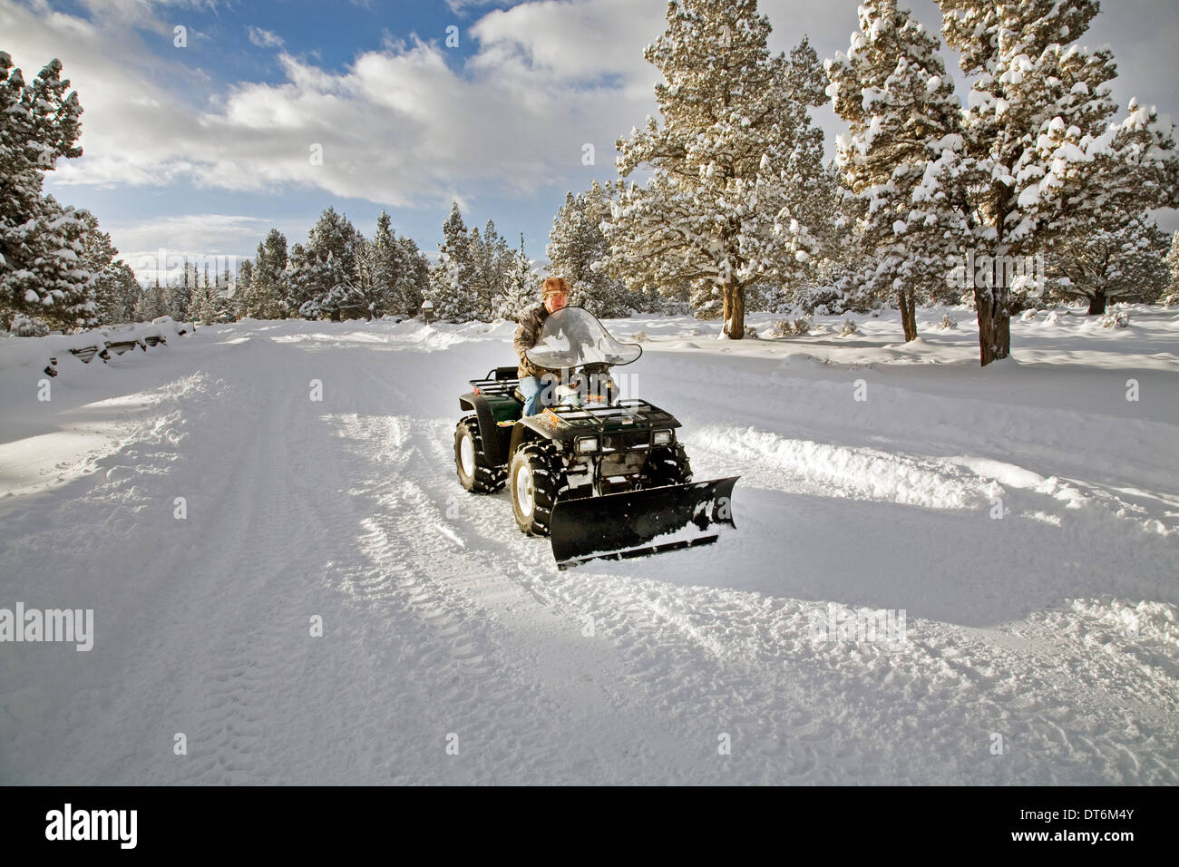 Una persona de la tercera edad los arados de nieve con un ATV, vehículo todo terreno, después de una gran tormenta de nieve en el centro de Oregon. Foto de stock