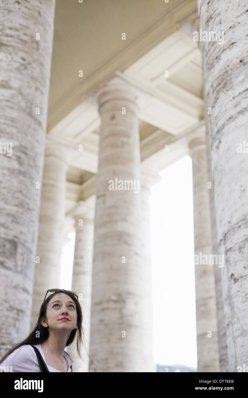 Una mujer mirando hacia los altos pilares y arcos de un edificio histórico, en Roma. Foto de stock