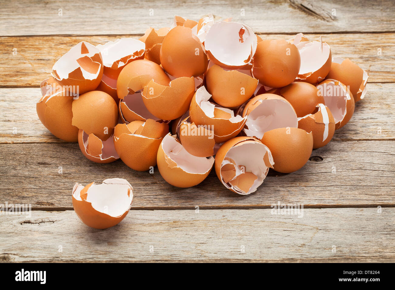 Un montón de cáscaras de huevo de pollo marrón blanco roto sobre una tabla de madera rústica Foto de stock