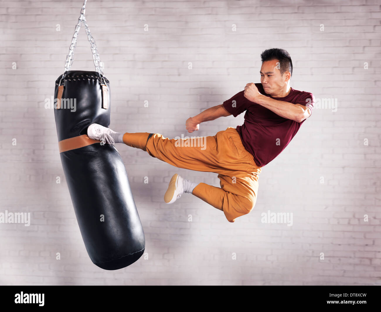Un artista marcial, instructor de Shaolin Kung Fu Shi Chang Dao patada voladora practicando en un saco de boxeo Foto de stock
