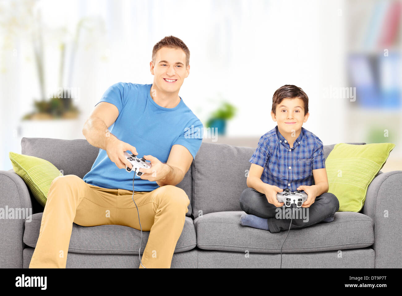 Joven jugar video juego con su primo más joven, en casa Foto de stock