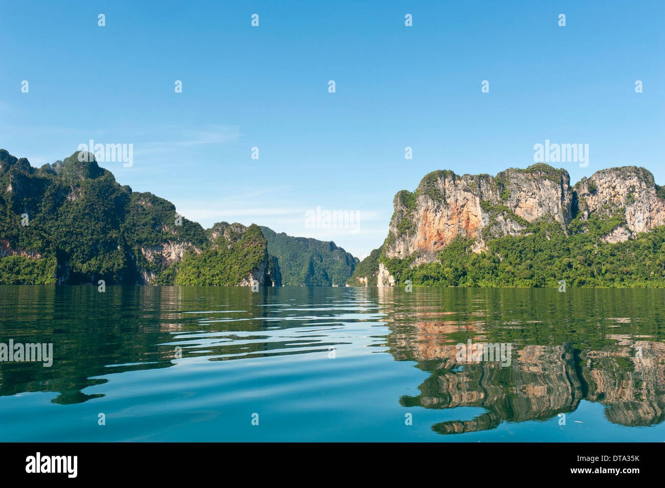 Karst boscosas montañas de piedra caliza se refleja en el agua, depósito Rachabrapha, Chiao Lago Léman, Parque Nacional de Khao Sok Foto de stock