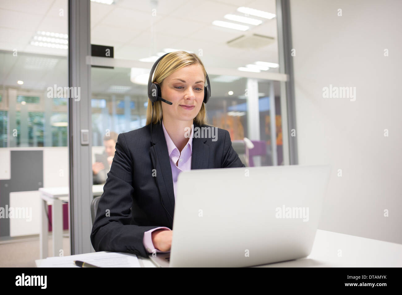 La empresaria en la oficina por teléfono con auriculares, video conferencia Foto de stock
