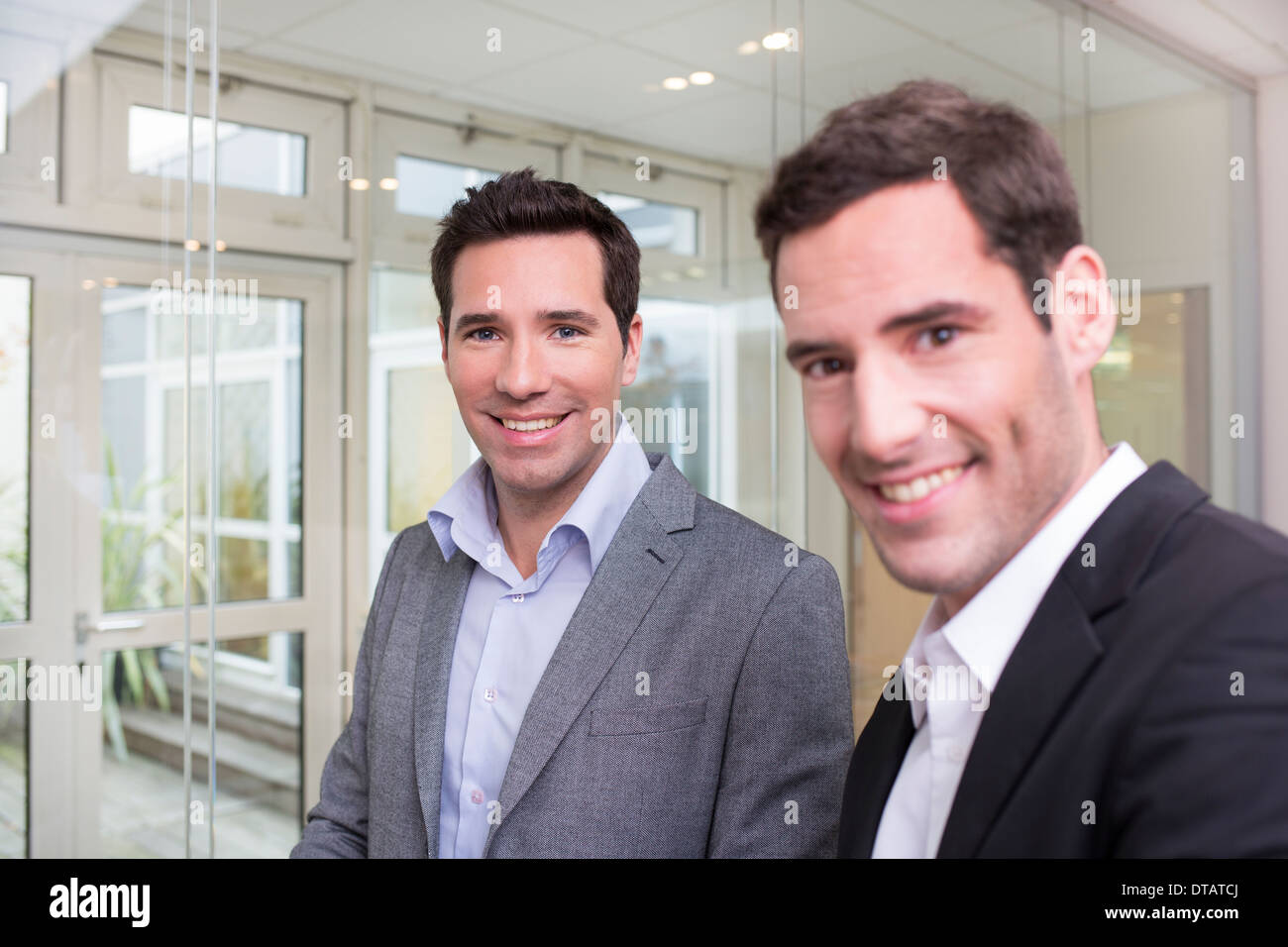 Retrato de dos empresarios sonrientes en oficina, mirando la cámara Foto de stock