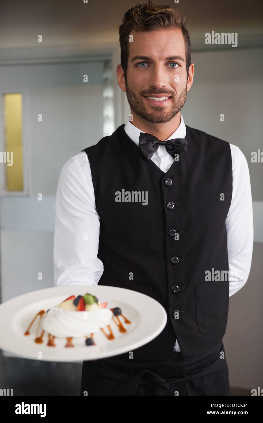 Camarero sonriente mostrando plato de postre a la cámara Foto de stock