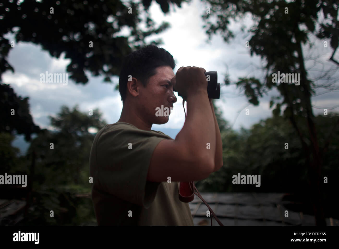 Un soldado del Kia utilice un prismáticos para observar el campamento enemigo en el Naw HPyu puesto en la línea de frente de la guerra Foto de stock