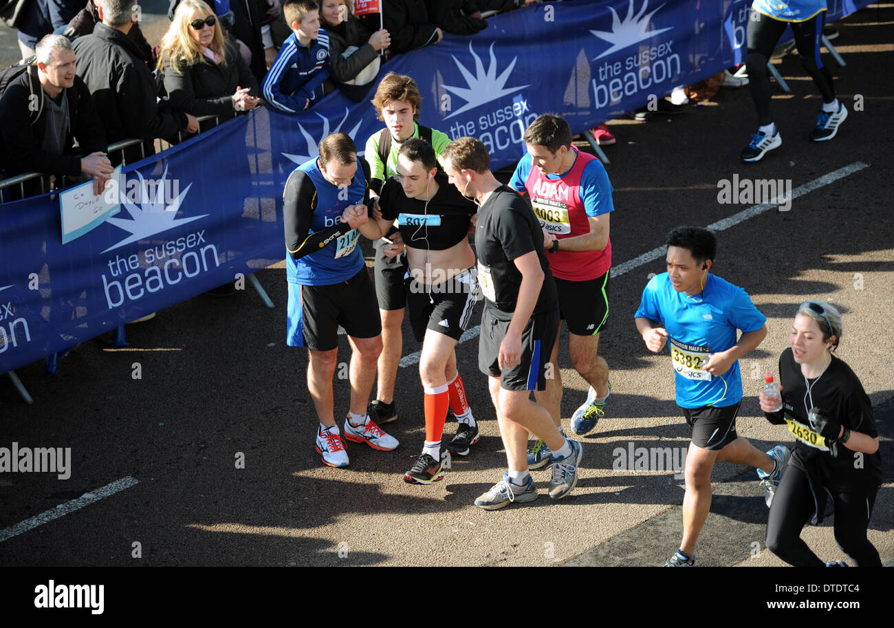 Armario explosión Sin Un corredor es ayudado a la línea de meta por su otros competidores como  más de 11000 corredores participan en el Media maratón de Brighton  Fotografía de stock - Alamy