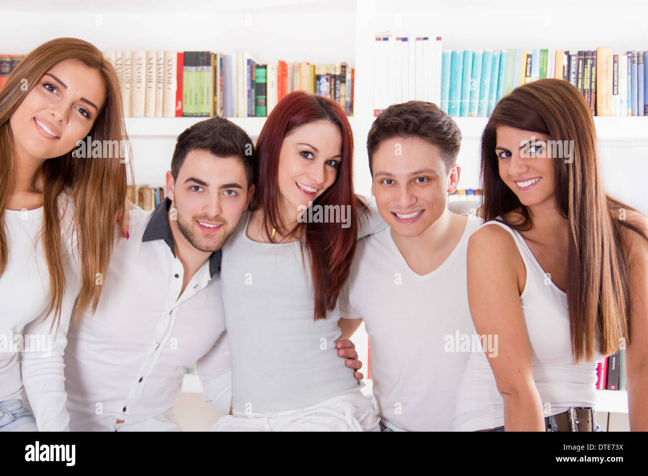 Retrato de un grupo de amigos, feliz y sonriente abrazando en casa Foto de stock