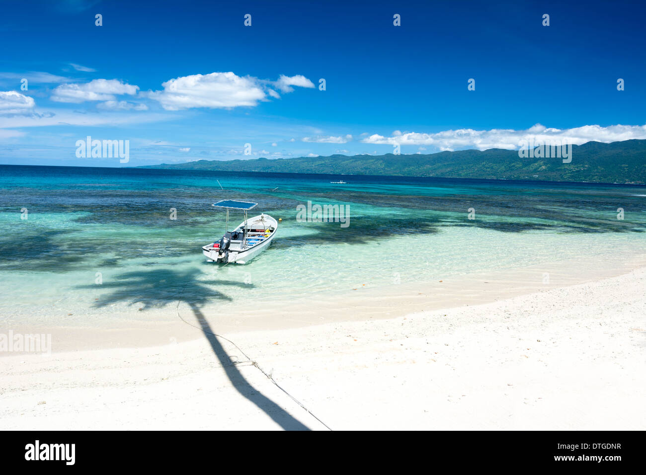 Hermosa playa tropical con agua clara que muestra un arrecife de coral y destaca un vibrante color azul profundo del cielo. Foto de stock