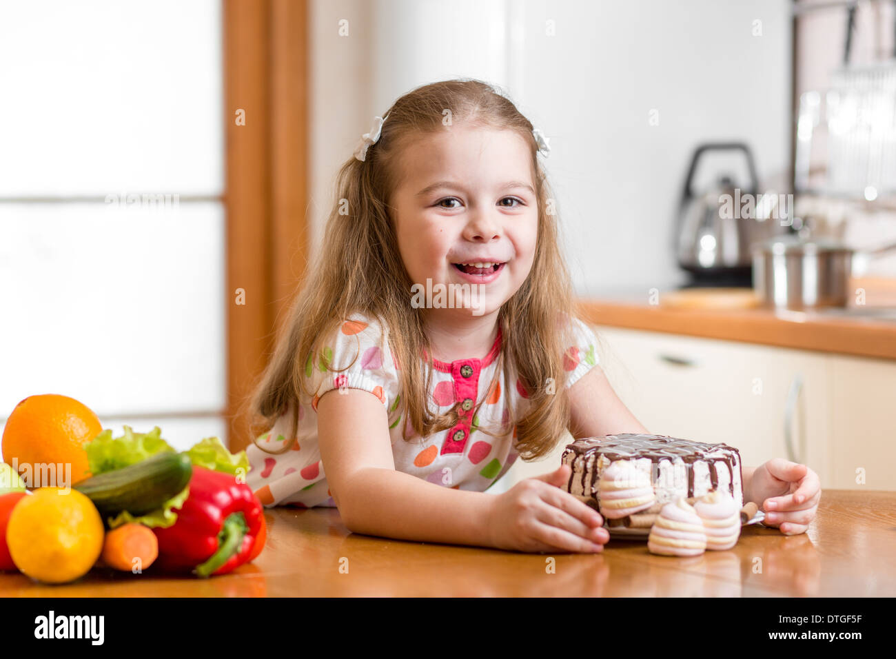Kid elegir entre verduras saludables y sabrosos dulces Foto de stock