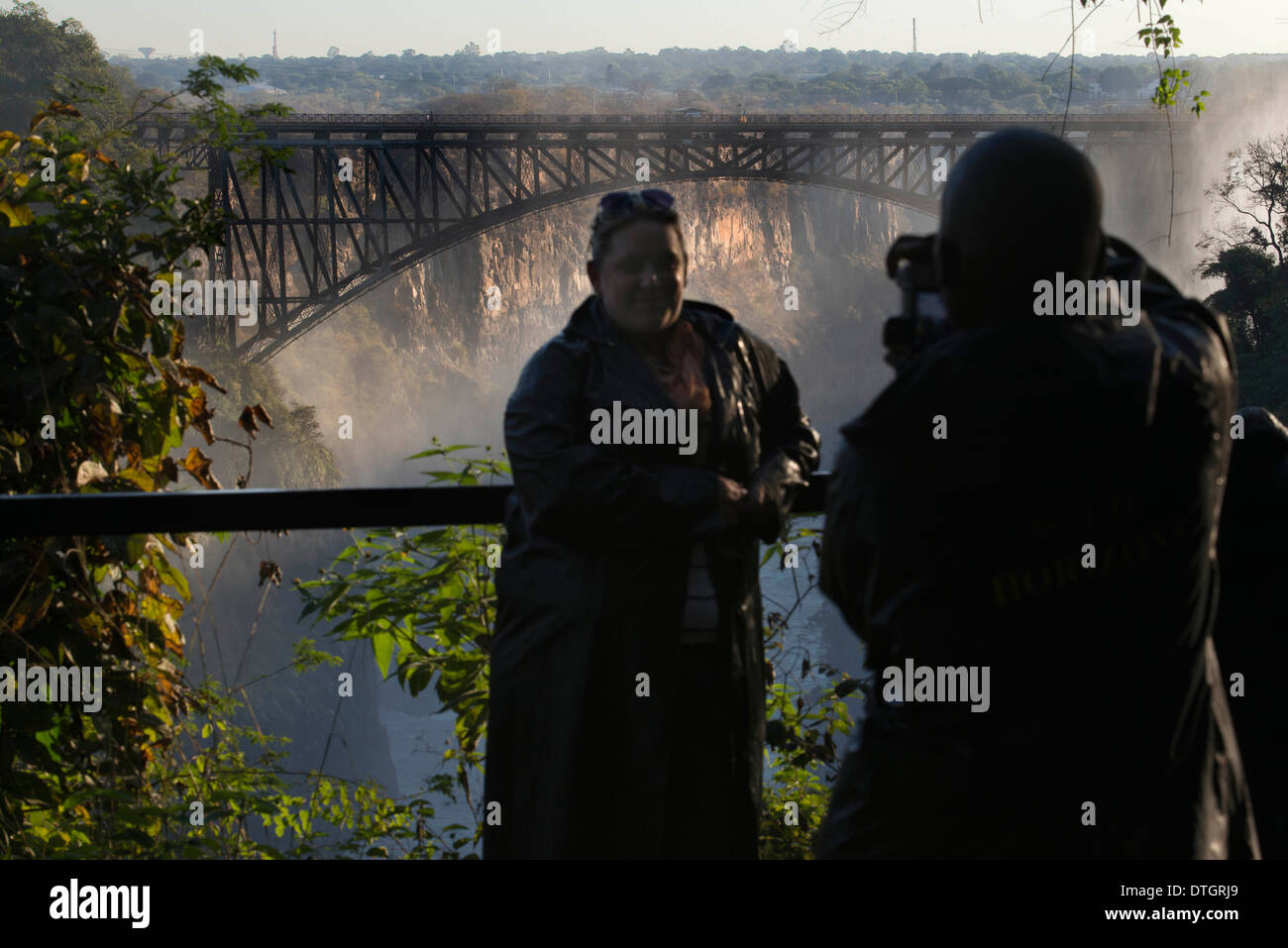 Una pareja toma fotos en Victoria Falls. Detrás del puente entre Zambia y Zimbabwe. Cruza el puente de Victoria Falls Foto de stock
