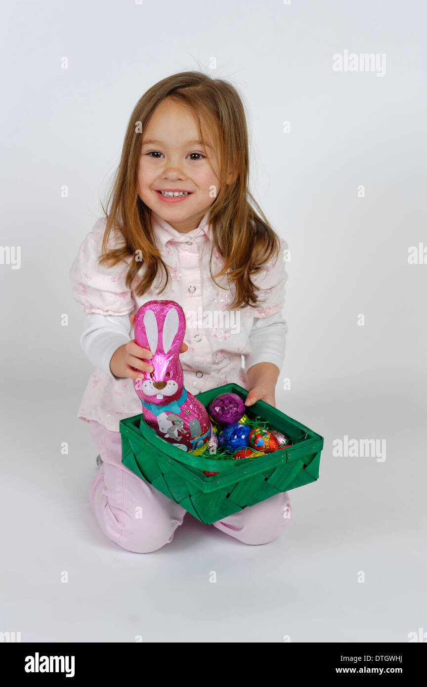 Chica está contento con una canasta y un conejito de Pascua de chocolate Foto de stock